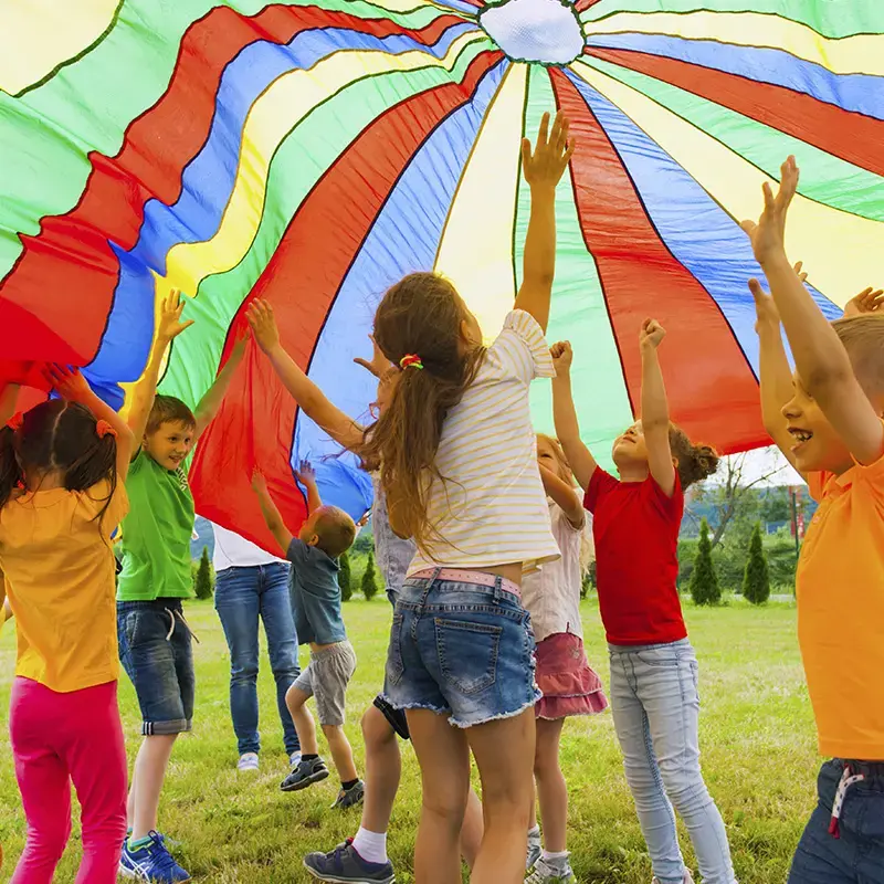 nens al jardí jugant amb una manta de colors, cursos de lleure per fer monitor